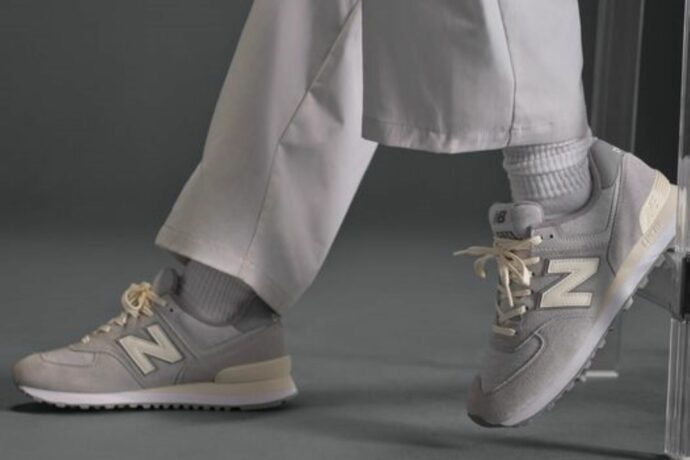 Osoba má na nohou šedé boty New Balance 574